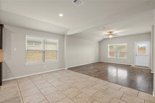 an empty room with wooden floor chandelier and windows