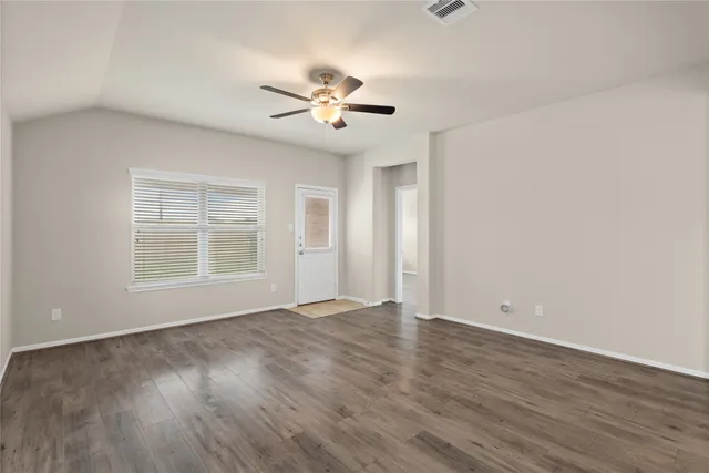 a view of an empty room with wooden floor and a window
