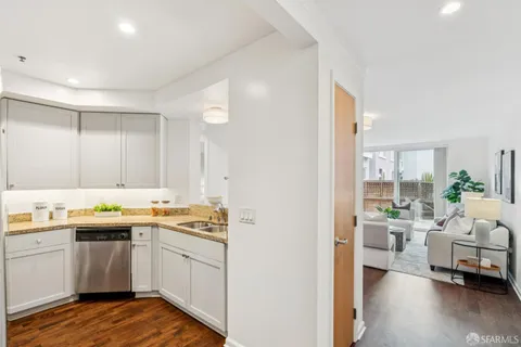 a view of a kitchen with a sink and dishwasher with wooden floor