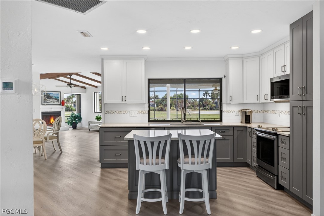 1312 Par View Drive Sanibel, FL 33957 - Photo 10 of 45 a kitchen with stainless steel appliances granite countertop a stove top oven a sink a refrigerator with a dining table and chairs with wooden floor
