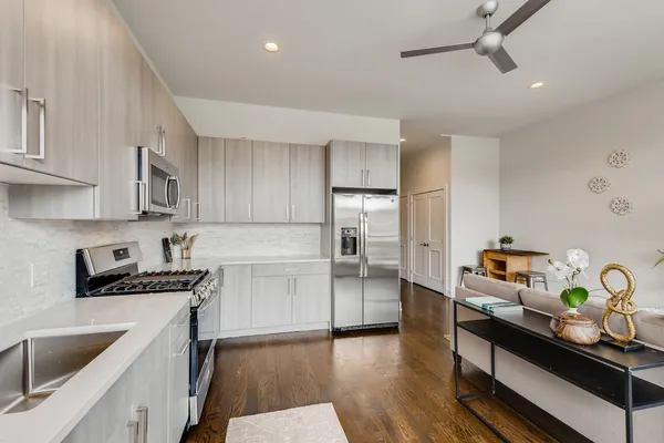 a kitchen with stainless steel appliances a sink dishwasher stove refrigerator and microwave with wooden floor