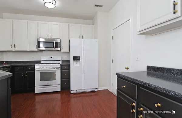 a kitchen with granite countertop a refrigerator and a stove top oven