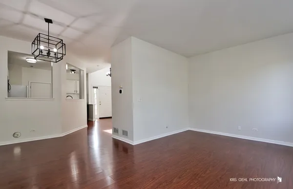 an empty room with wooden floor and chandelier