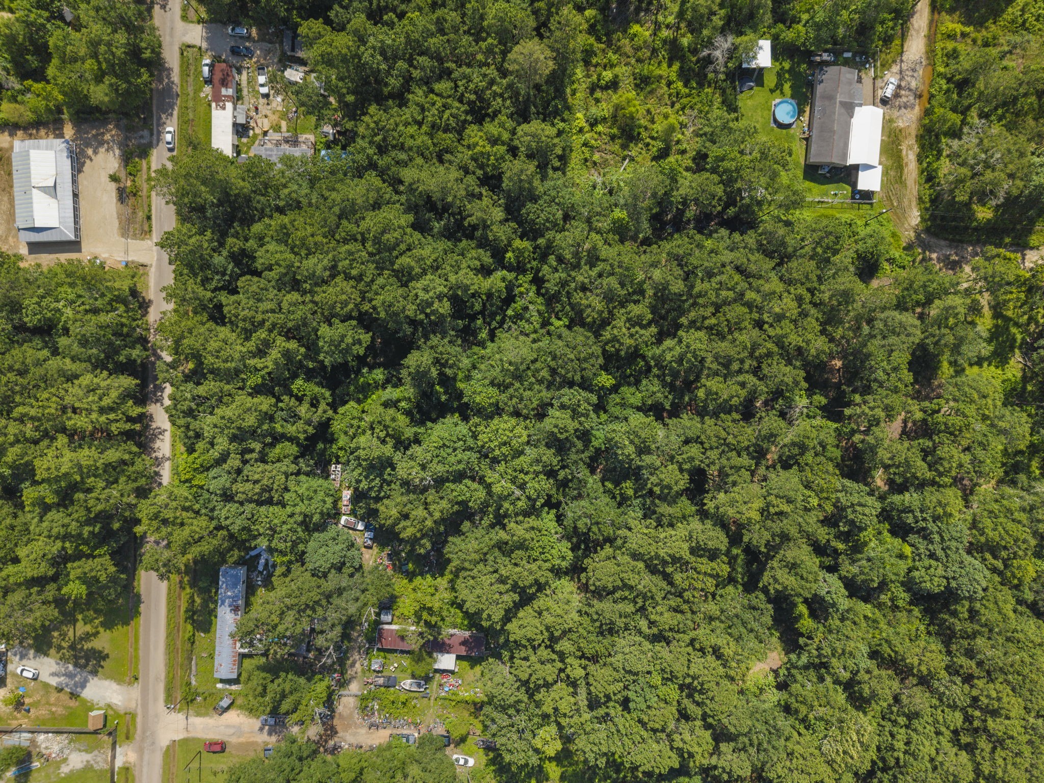 15597 Westgate Road Splendora, TX 77372 - Photo 4 of 14 Overhead Lot Context - Top-down drone angle gives buyers a clearer sense of the wooded terrain, neighboring properties, and general site context.