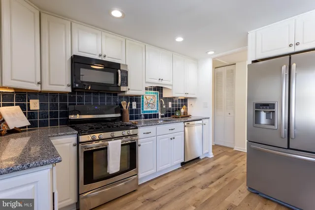 a kitchen with granite countertop a sink a stove and cabinets
