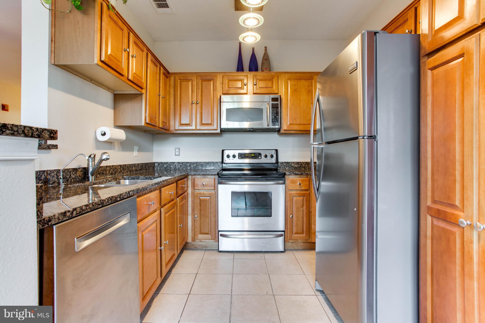 1600 Spring Gate Dr., Unit 2207 McLean, VA 22102 - Photo 11 of 29 a kitchen with stainless steel appliances granite countertop a refrigerator a stove and a sink with wooden floor