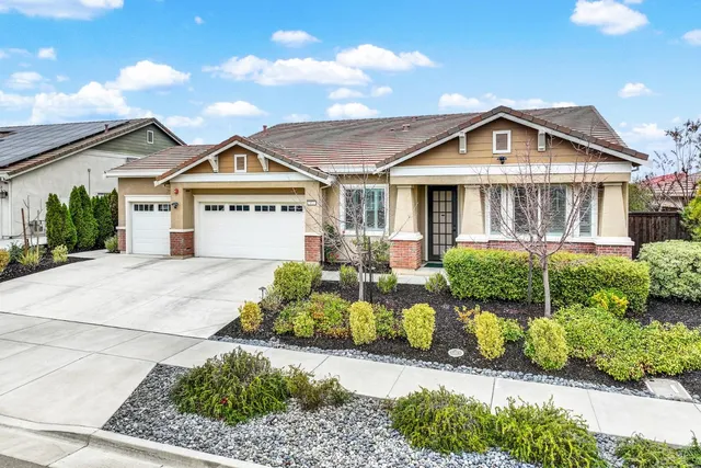a front view of a house with a yard and potted plants