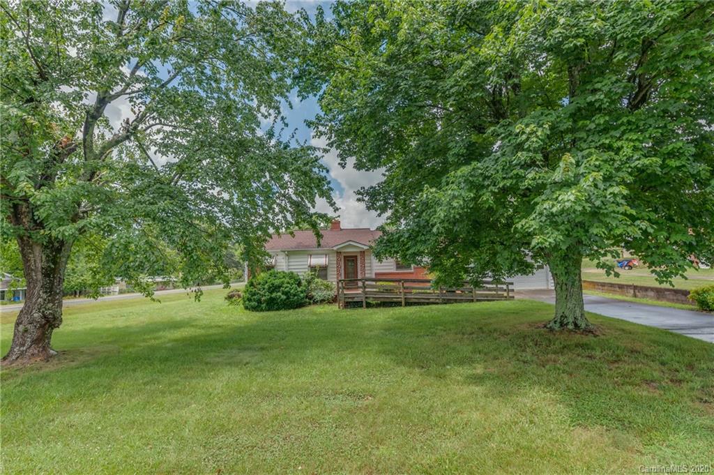 a view of a house with a big yard and large trees