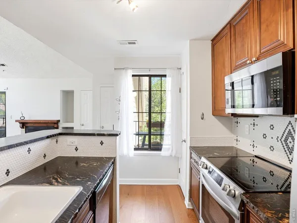 a kitchen with granite countertop a sink a stove and cabinets