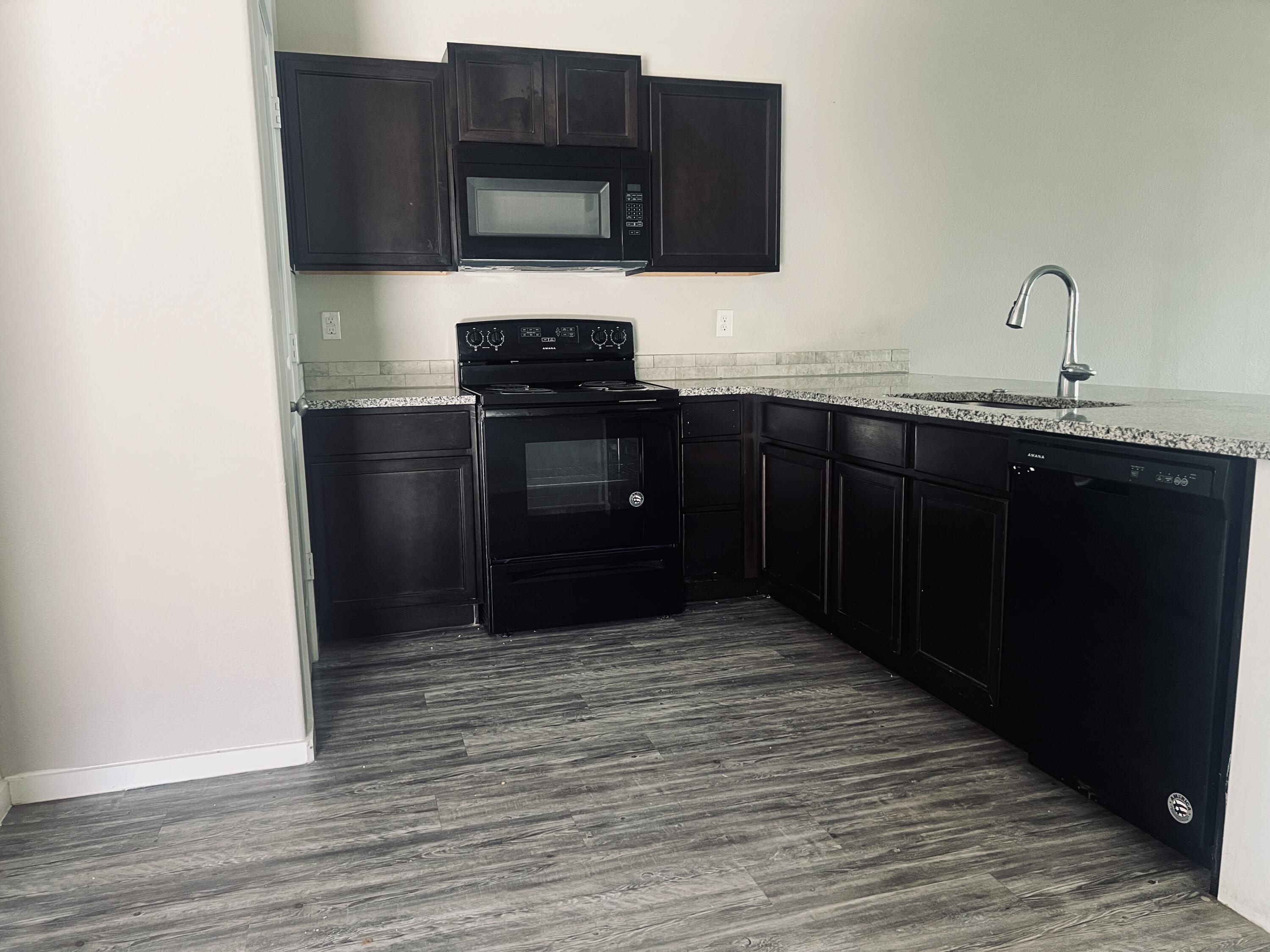 1637 133rd Street, Unit B Lubbock, TX 79423 - Photo 2 of 19 a kitchen with stainless steel appliances granite countertop a refrigerator and a stove top oven