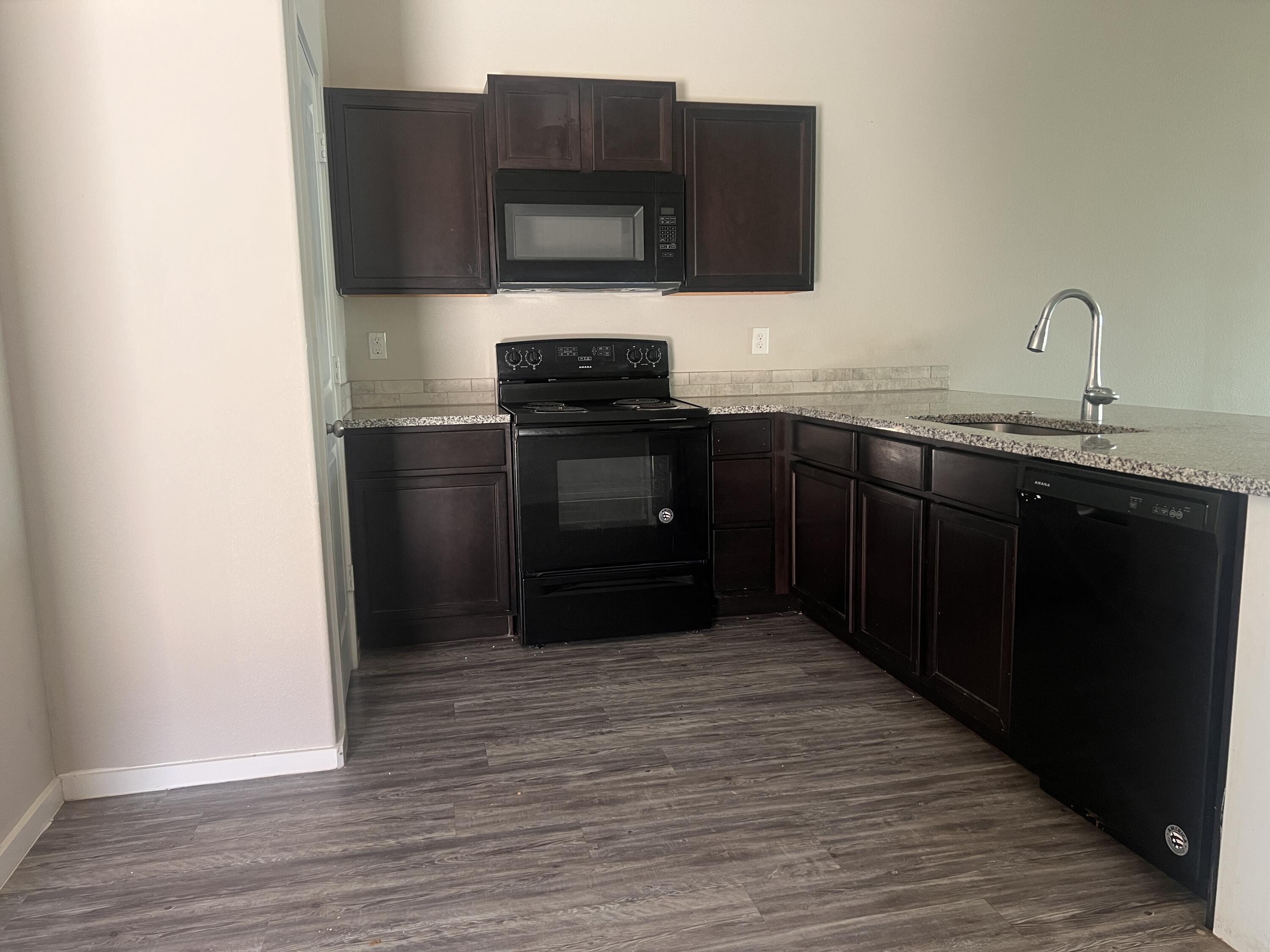 1637 133rd Street, Unit B Lubbock, TX 79423 - Photo 4 of 19 a kitchen with stainless steel appliances granite countertop a stove and a microwave