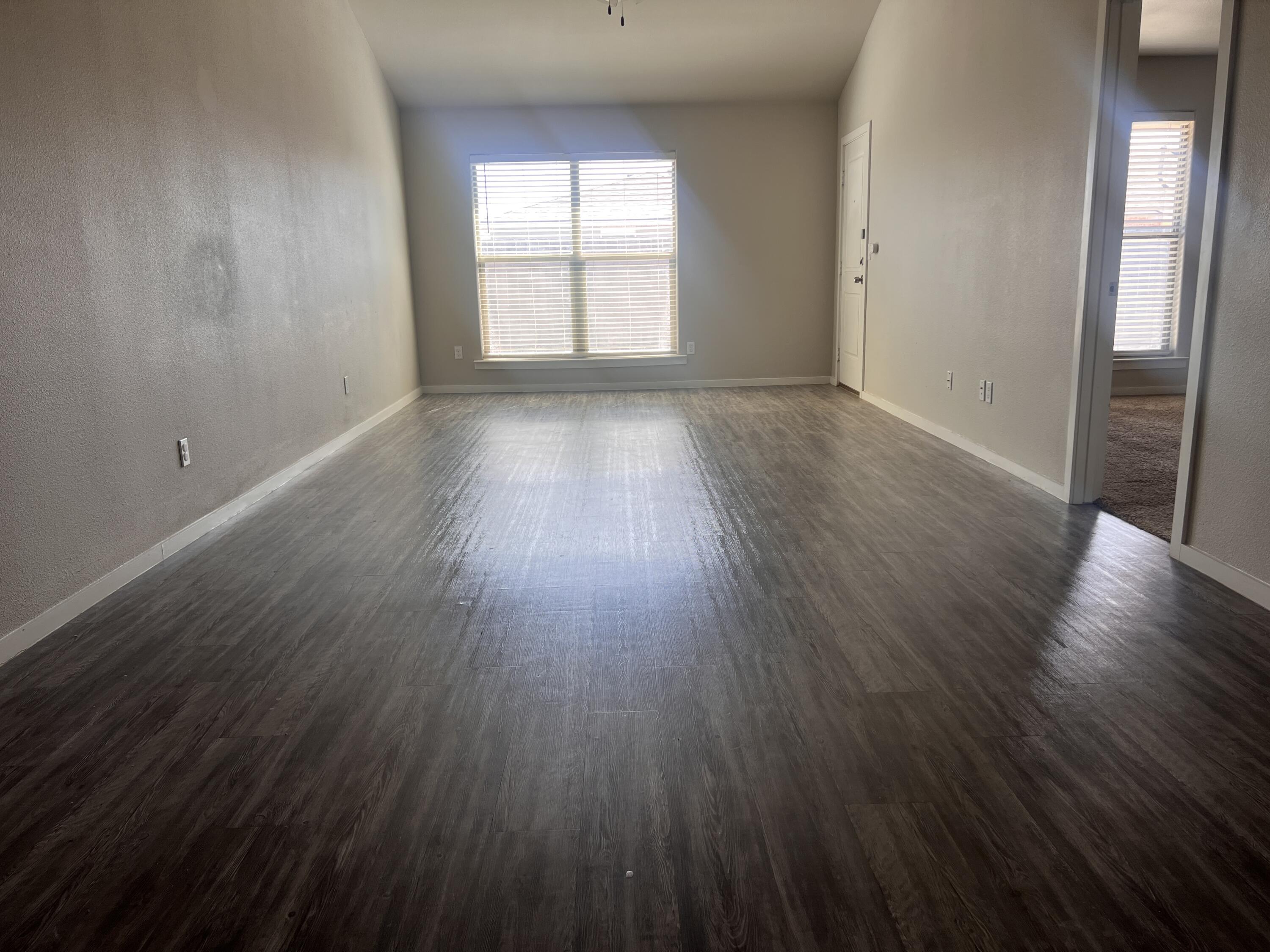 1637 133rd Street, Unit B Lubbock, TX 79423 - Photo 6 of 19 an empty room with wooden floor and windows