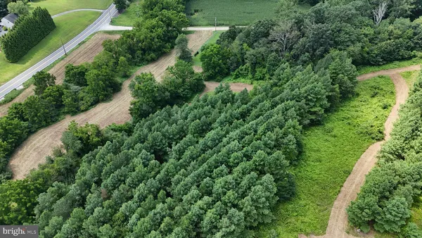 an aerial view of residential house with outdoor space and trees all around