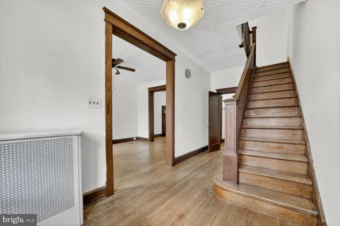 a view of a hallway with wooden floor and staircase