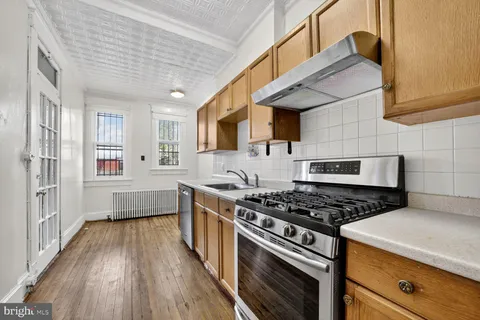 a kitchen with stainless steel appliances a stove a sink dishwasher and cabinets with wooden floor