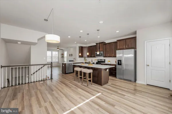 a kitchen with stainless steel appliances granite countertop a stove a sink dishwasher a refrigerator white cabinets and wooden floor