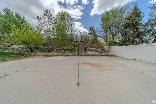 598 Hollow Creek Road Draper, UT 84020 - Photo 101 of 110 Concrete sports court featuring a basketball hoop, established landscaping, and a white privacy fence