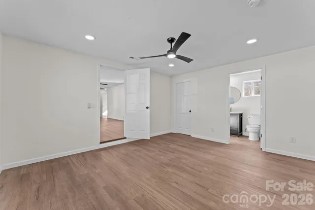 a view of an empty room with wooden floor and a ceiling fan