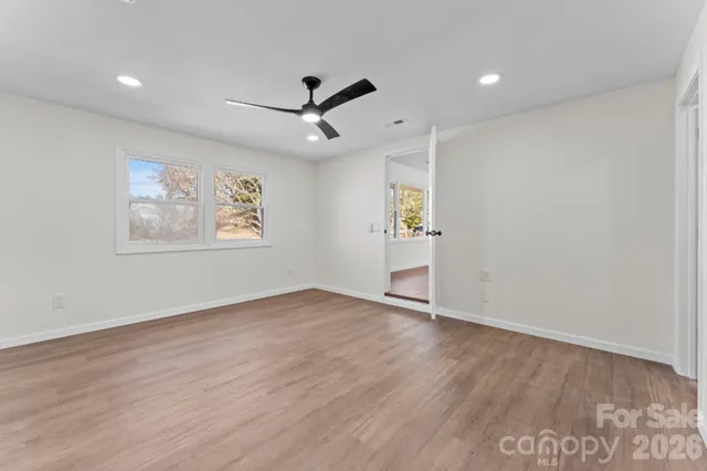 an empty room with wooden floor ceiling fan and window