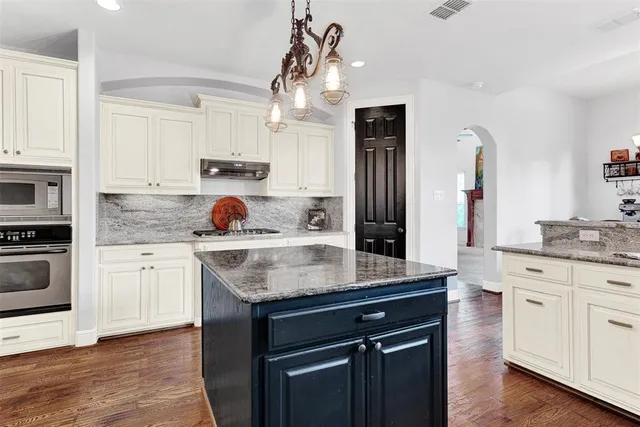 a kitchen with granite countertop a counter top space a sink cabinets and wooden floor