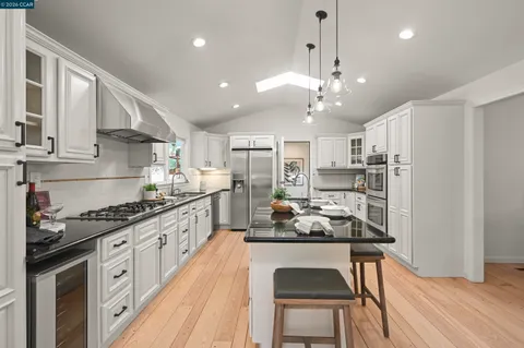 a kitchen with granite countertop a stove a sink and a refrigerator