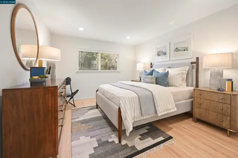 a spacious bedroom with a bed a mirror and a table in it