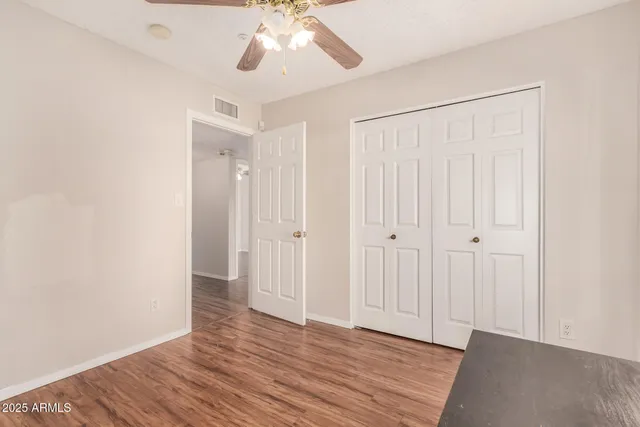 an empty room with wooden floor closet and windows