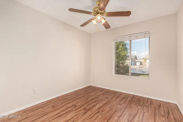 an empty room with wooden floor fan and windows