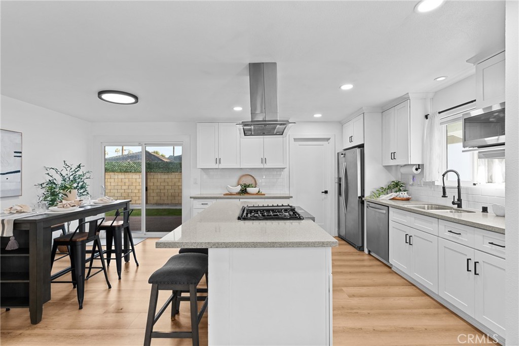225 South Feldner Road Orange, CA 92868 - Photo 5 of 40 a kitchen with stainless steel appliances a stove a sink a kitchen island and chairs with wooden floor
