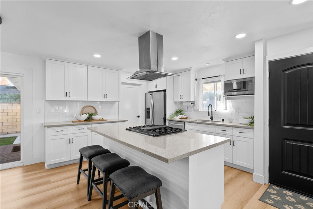 225 South Feldner Road Orange, CA 92868 - Photo 9 of 40 a kitchen with stainless steel appliances a stove a sink dishwasher a refrigerator and white cabinets with wooden floor