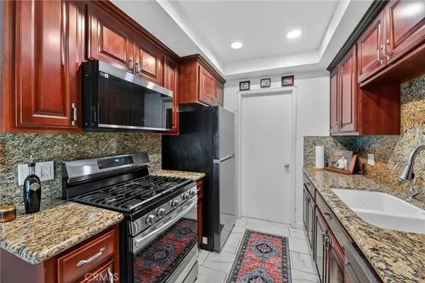 a kitchen with granite countertop a sink stove and refrigerator