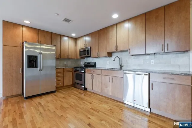 a kitchen with granite countertop a refrigerator sink and cabinets