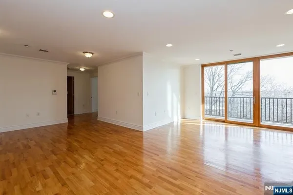 a view of an empty room with wooden floor and a window