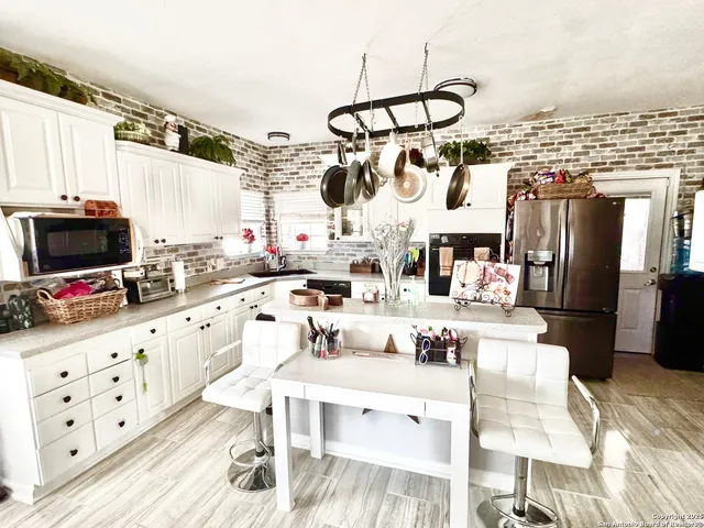 a kitchen with stainless steel appliances kitchen island granite countertop a refrigerator a stove a sink dishwasher and white cabinets with wooden floor