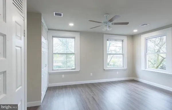a view of an empty room with wooden floor and window