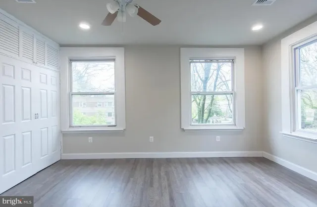 an empty room with wooden floor and windows