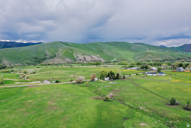 6700 North Capitol Hill Road Preston, ID 83263 - Photo 27 of 28 Expansive green fields with rolling hills, distant mountain backdrop, and scattered rural structures