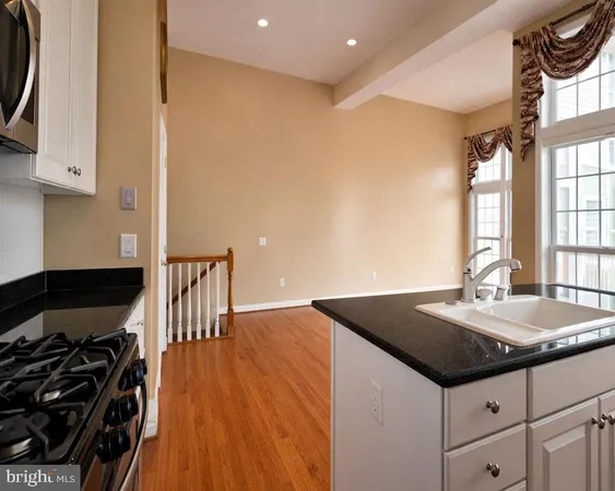 a kitchen with granite countertop a sink a stove and a wooden floor