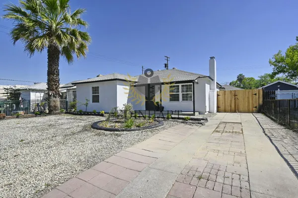 a front view of a house with garden and trees