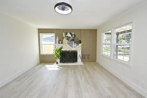 an empty room with windows a fireplace and wooden floor