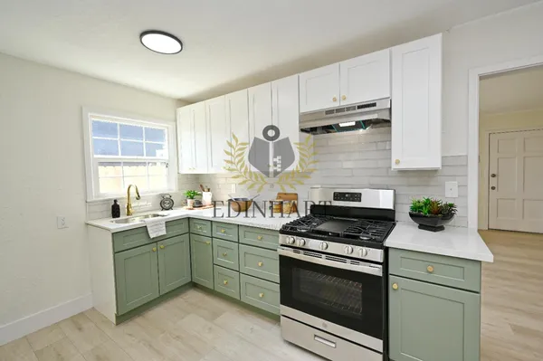 a kitchen with granite countertop a sink cabinets stainless steel appliances and a window