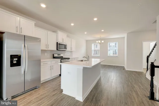 a kitchen with stainless steel appliances granite countertop a refrigerator a sink dishwasher a stove top oven a refrigerator with wooden floor