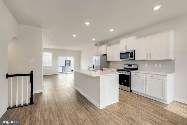 a kitchen with white cabinets appliances and wooden floor