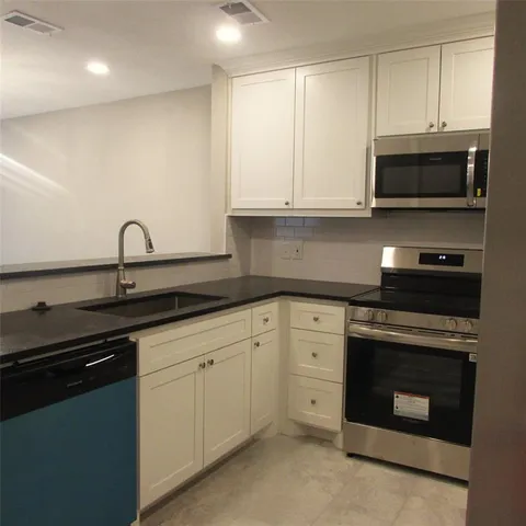 a kitchen with white cabinets and appliances