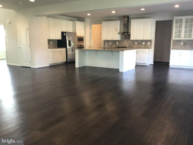 a view of kitchen with kitchen island wooden floors wooden cabinets and appliances