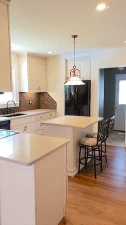 45 Wachusett Street Springfield, MA 01118 - Photo 7 of 23 a kitchen with kitchen island a stove a microwave a dining table and chairs with wooden floor