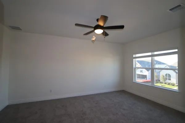 an empty room with windows and ceiling fan