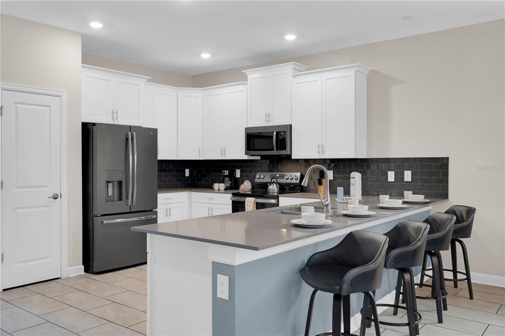 4530 Narrative Lane Kissimmee, FL 34746 - Photo 17 of 98 a kitchen with stainless steel appliances granite countertop a refrigerator and a stove top oven