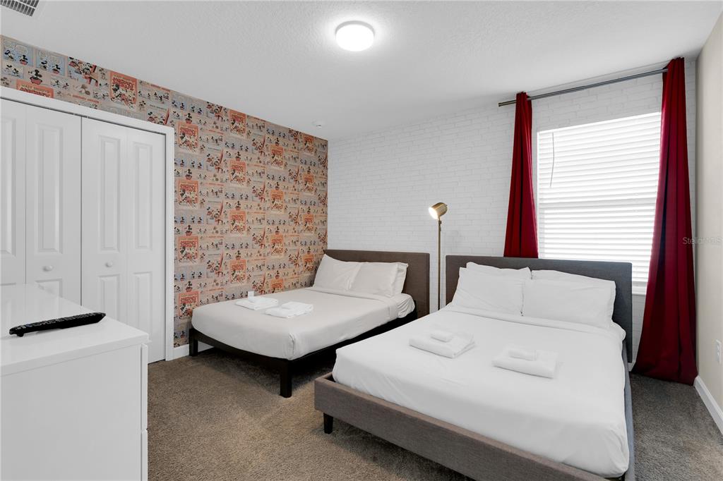 4530 Narrative Lane Kissimmee, FL 34746 - Photo 60 of 98 a bedroom with two beds and a chandelier