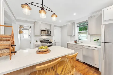 a kitchen with a sink a stove a refrigerator and white cabinets